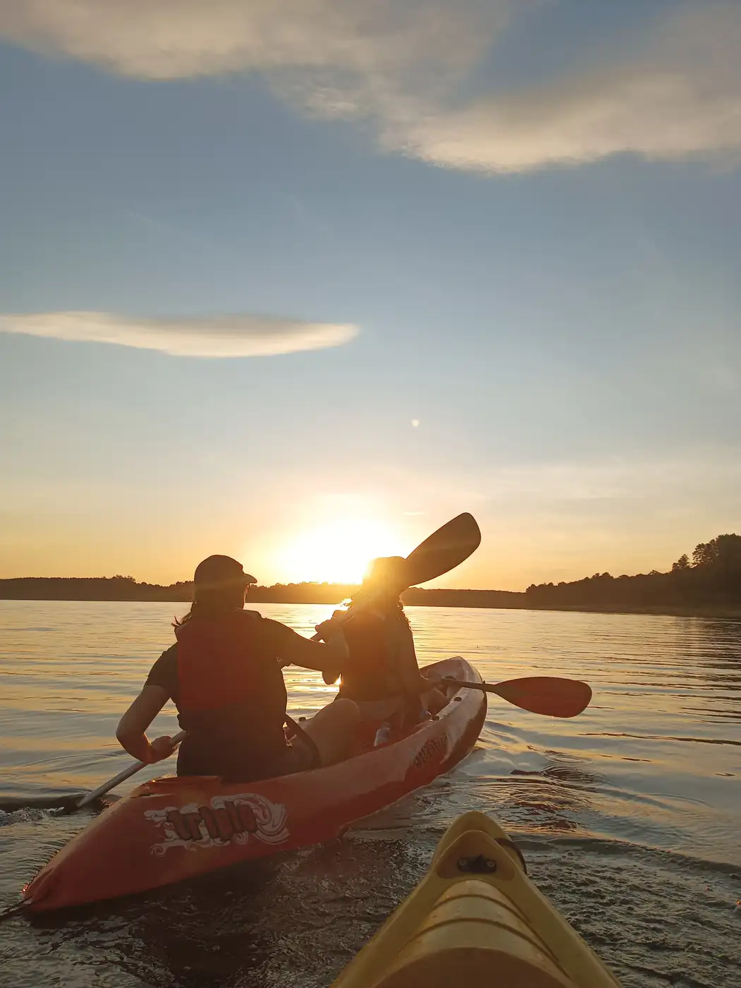 Dos personas reman un kayak sobre el lago Urugua-í al atardecer.