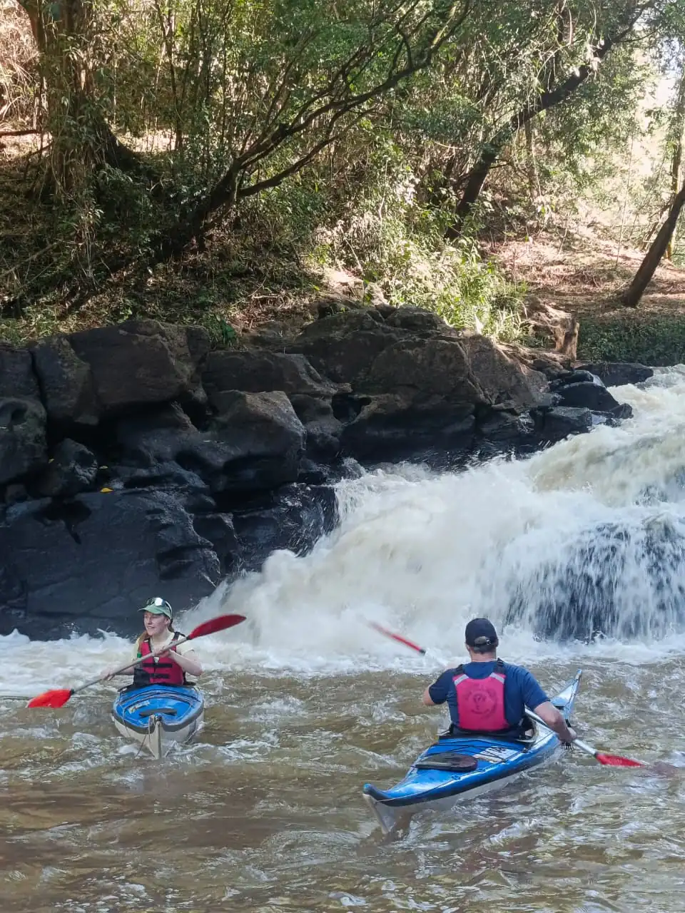 A kayak drops into the rapid with water breaking over the rocks.